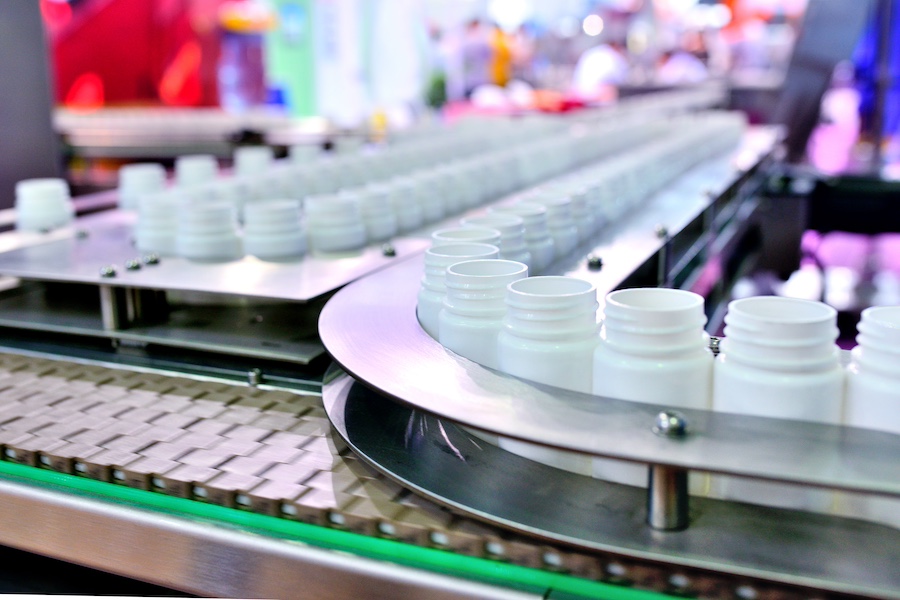 Empty bottles for cosmetic or beauty products are moved through a production line in a contract manufacturing factory.