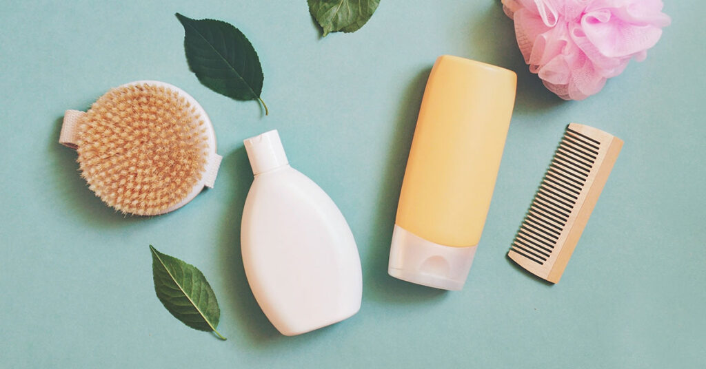 Several white-label hair care products and tools on a green background, interspersed with green leaves.