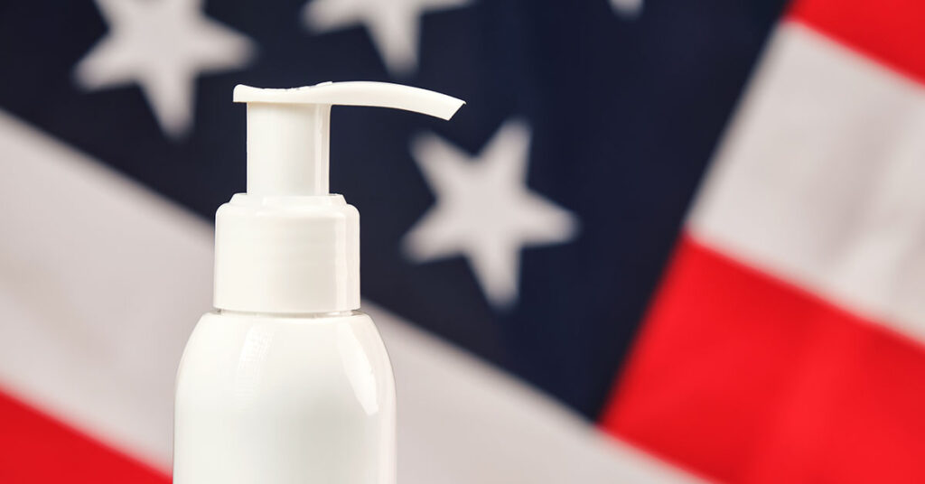 A white-label hair care product bottle with a pump-style top produced by a CMO, with an American flag in the background